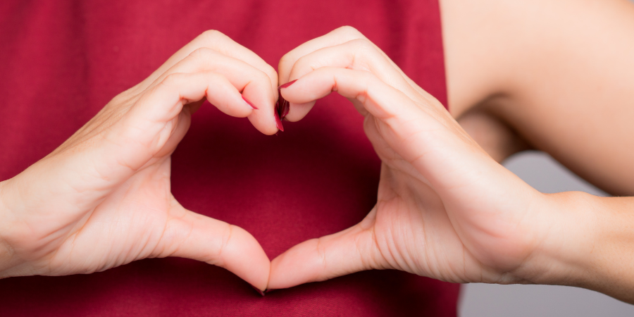 A woman’s heart-shaped hands over her heart and red dress, for February American Heart Month and health tips from Advantia Health.